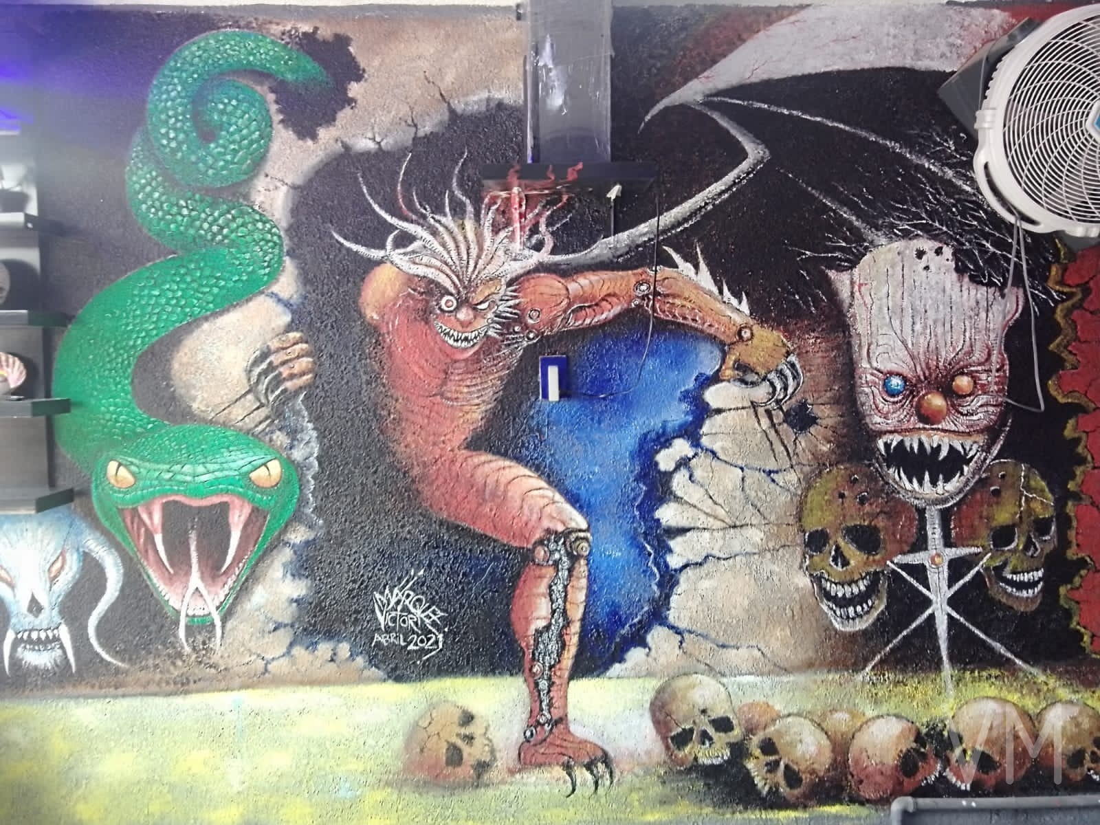 Mural épico con serpiente gigante, demonio y rostro estilo Eddie de Iron Maiden entre calaveras.